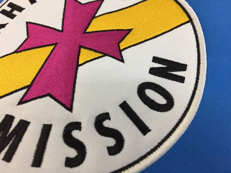 Detailaufnahme der Stickerei der Bahnhofs Mission